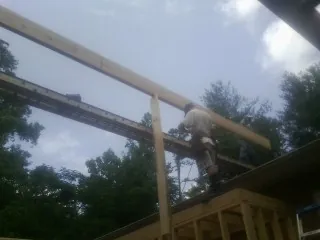 Carpenter setting a ridge beam over a new addition frame — Ice Dam Removal by Roofing Brothers in Redvale