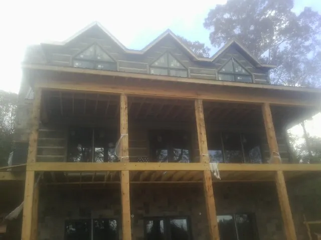 Dormers and porch framing on a large log home under construction — Roof Coating work by our crew in Redvale