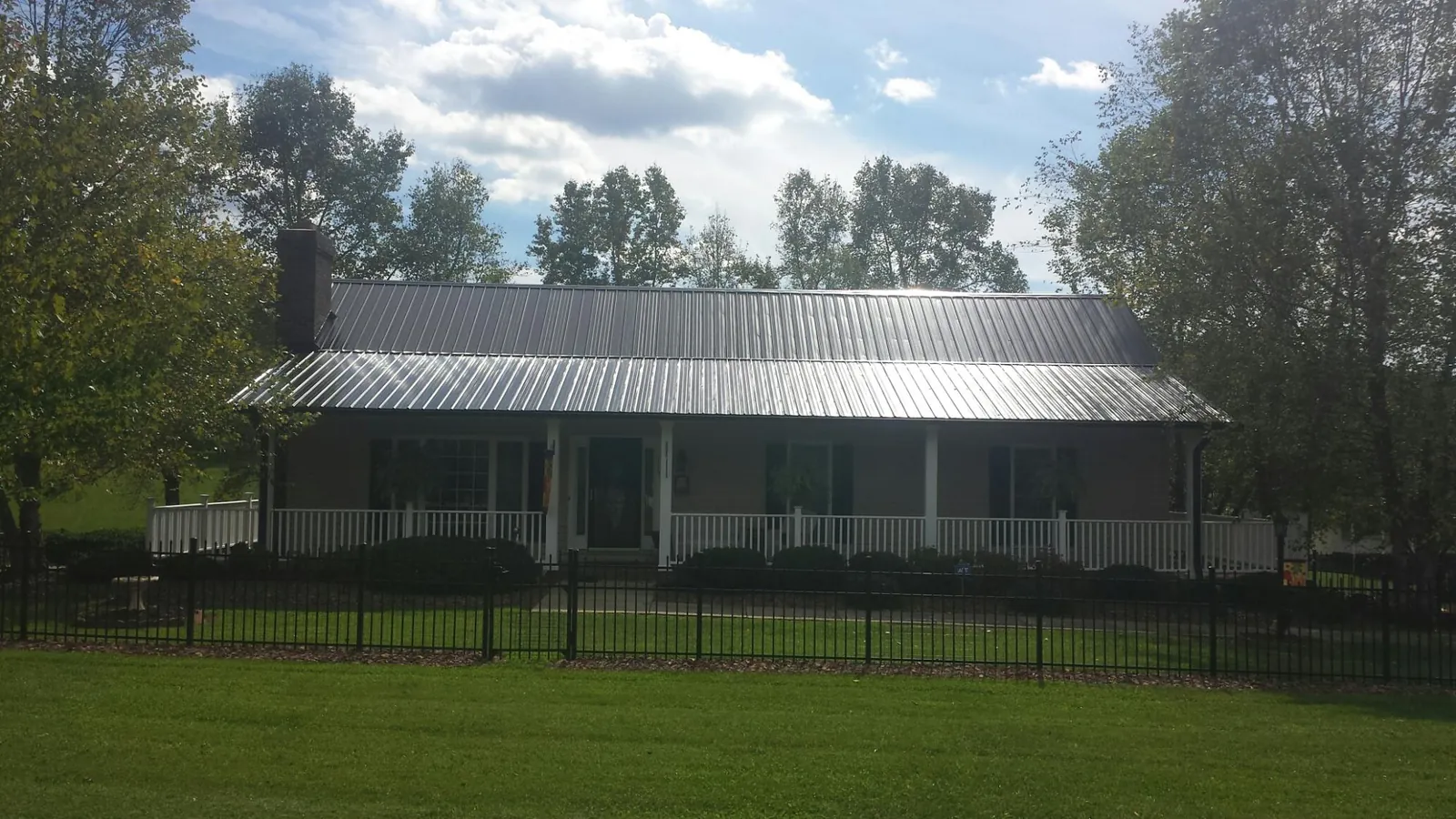 Gray metal roof on a brick ranch with a full width front porch — Gutter Guard Installation work by our crew in Redvale