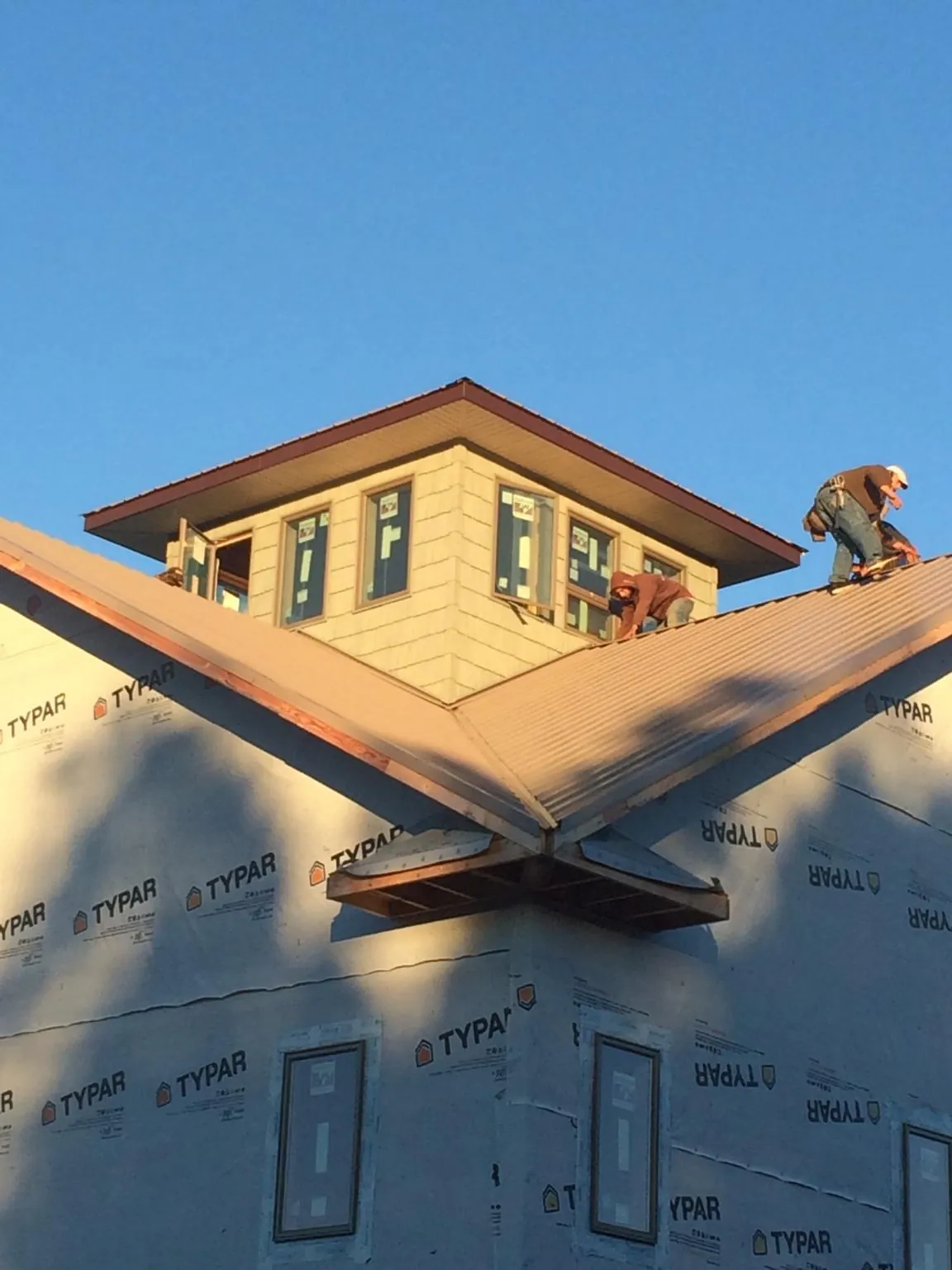 Roofers working around a rooftop cupola on a new metal roof at sunset — Roof Waterproofing in Redvale by Roofing Brothers